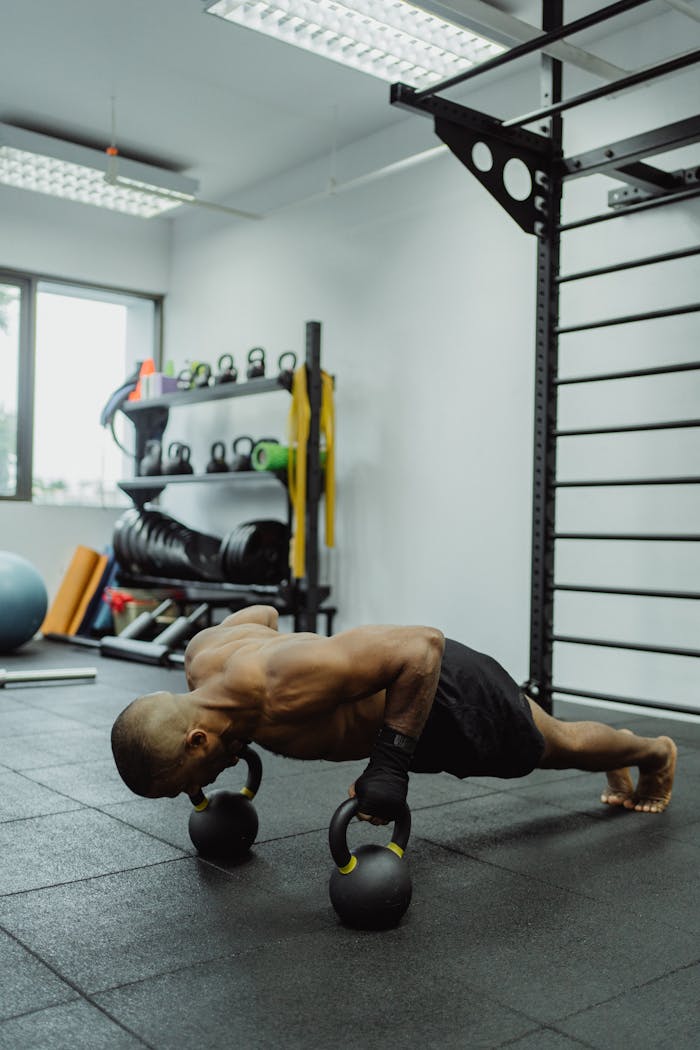 services-01 Athletic man doing push-ups on kettlebells in a modern gym setting.