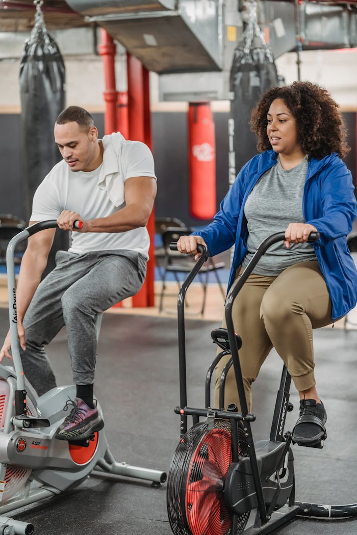 services-02 Full body of male and female in sportswear sitting on cycling machines in contemporary gym