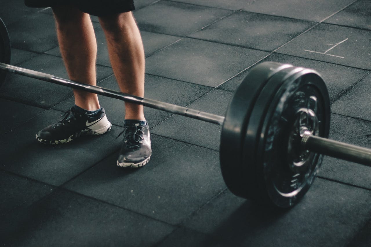 hero-img-02 Close-up of a man deadlifting a heavy barbell in an indoor gym setting.