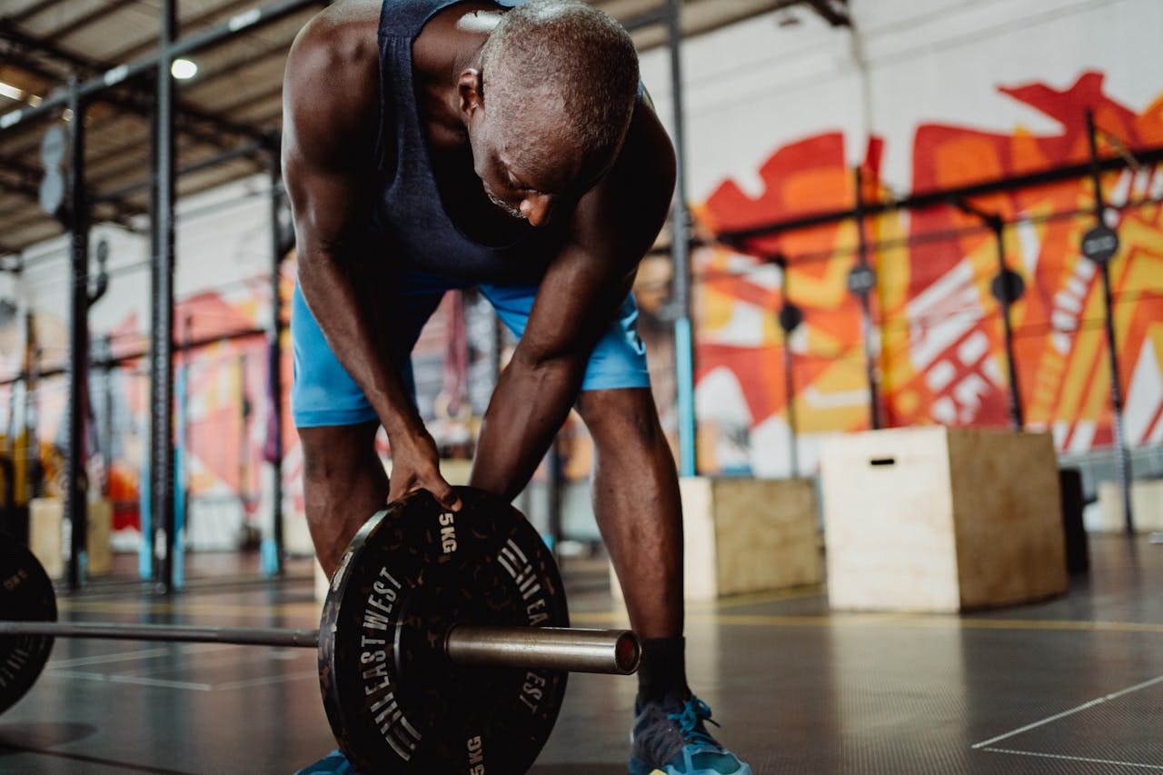about-01 Athletic man lifting weights in a modern gym with urban art decor, showcasing strength and fitness.